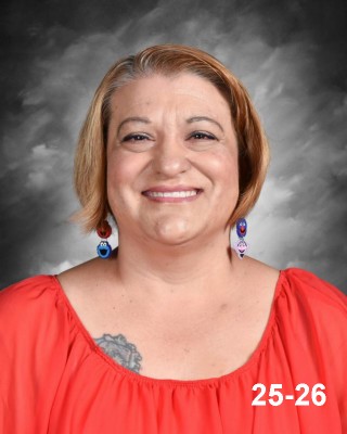 Smiling woman with short hair, wearing a red top and colorful earrings, against a gray background.
